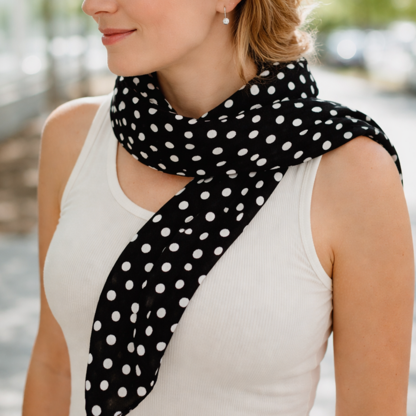 Woman wearing a black polka dot scarf in an outdoor setting