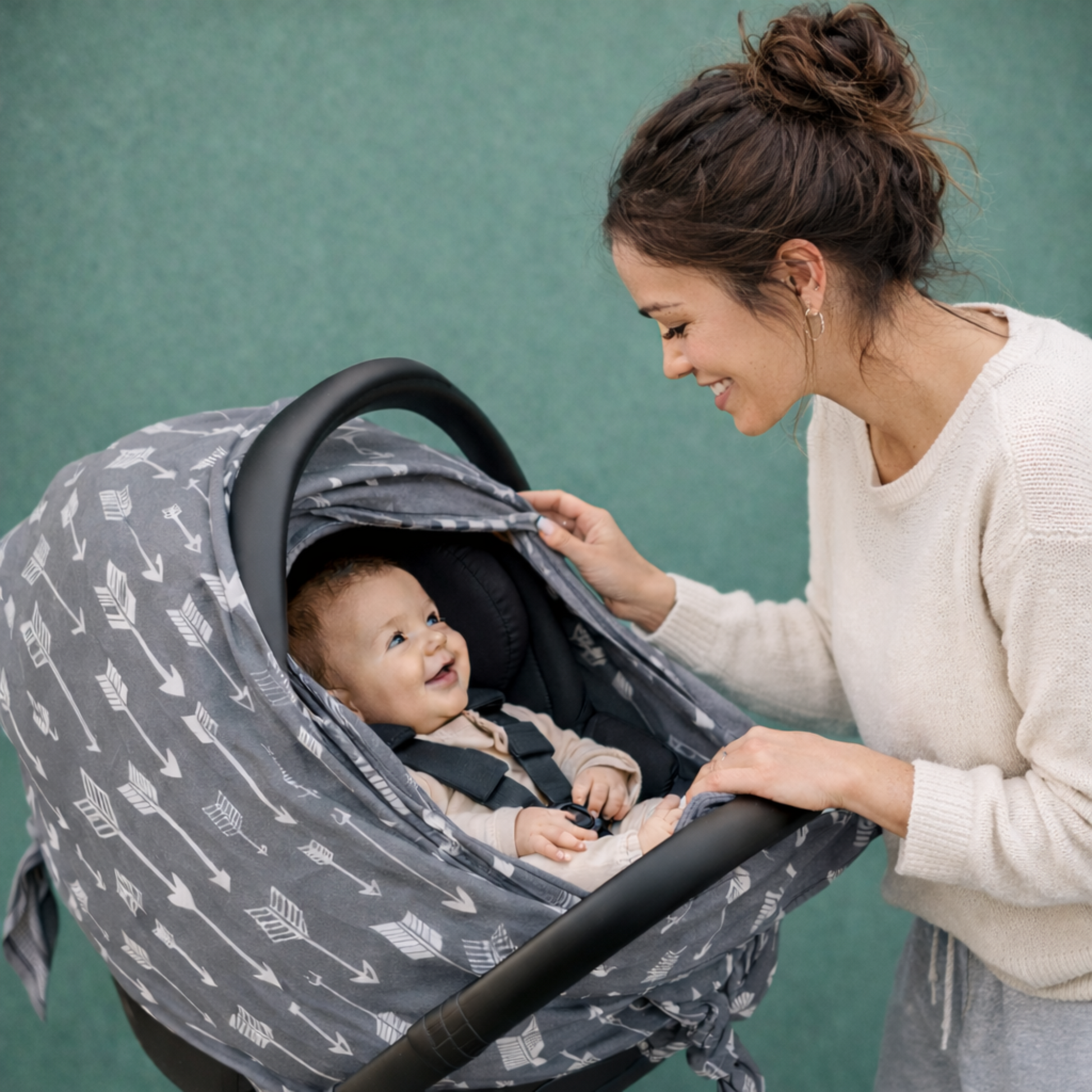Mom opening a grey baby car seat  cover with zipper with infant inside the