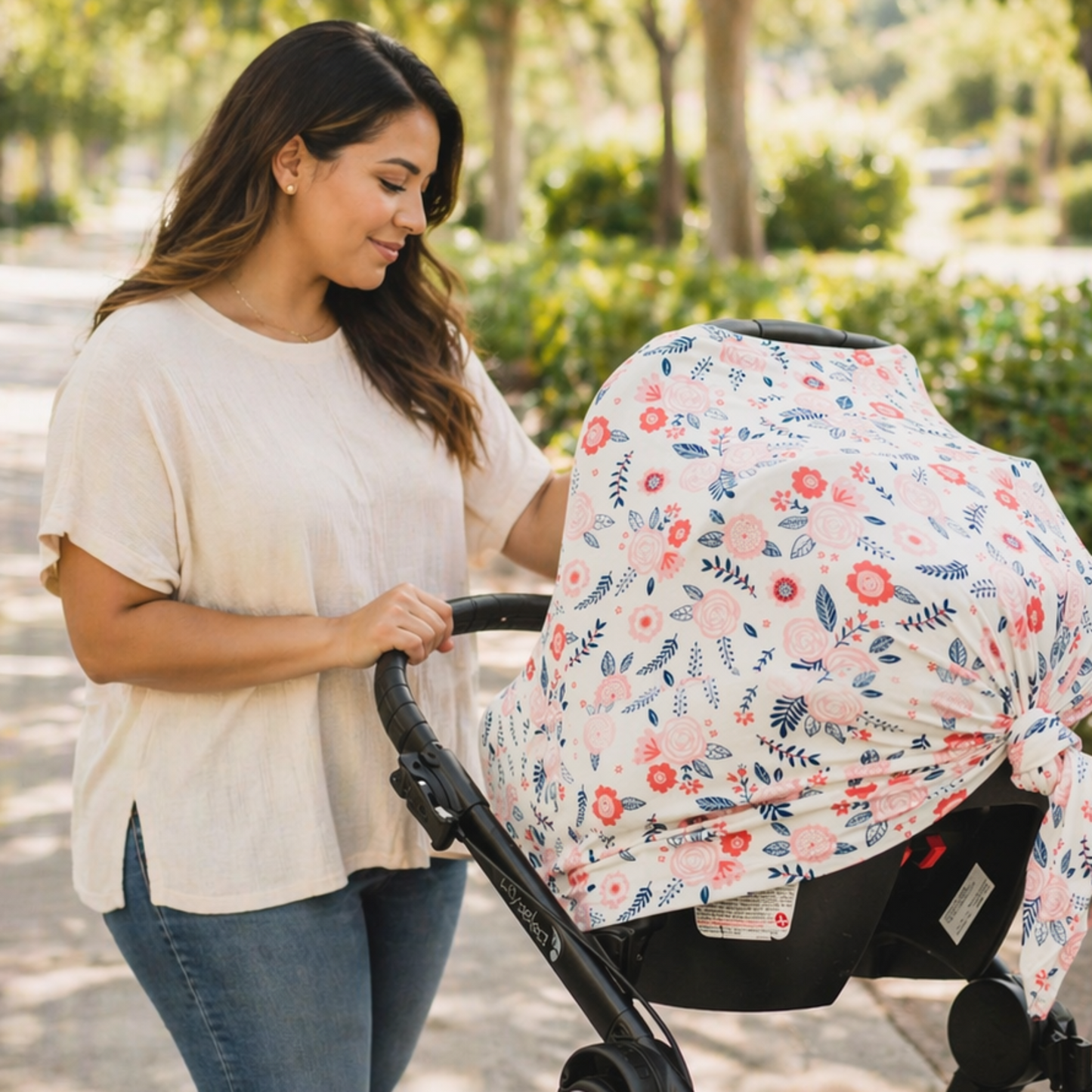 Woman pushing a stroller with a floral baby car seat canopy in a park