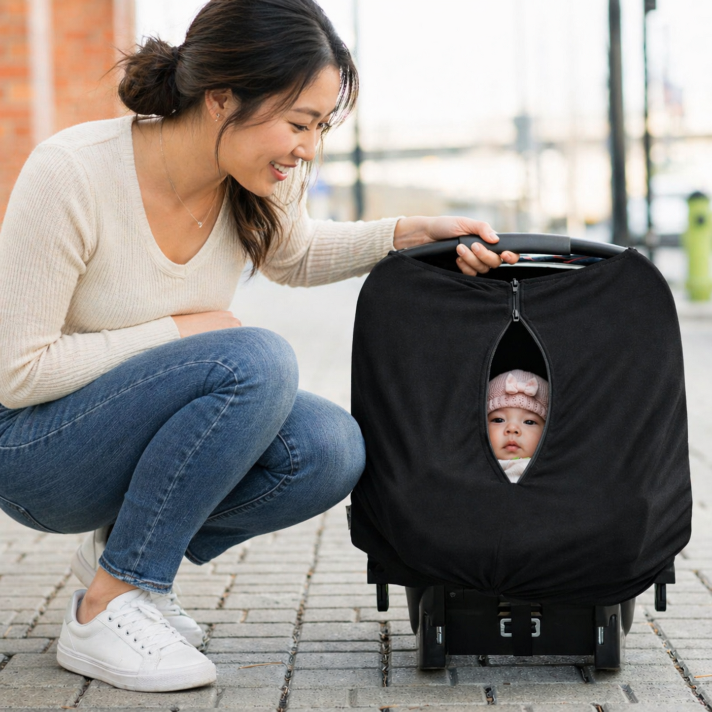 Woman with a baby in a stroller cover on a sidewalk