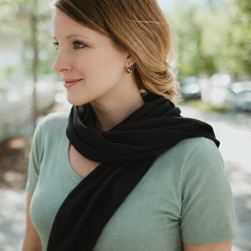 Woman wearing a black scarf over her shoulder with a blurred outdoor background