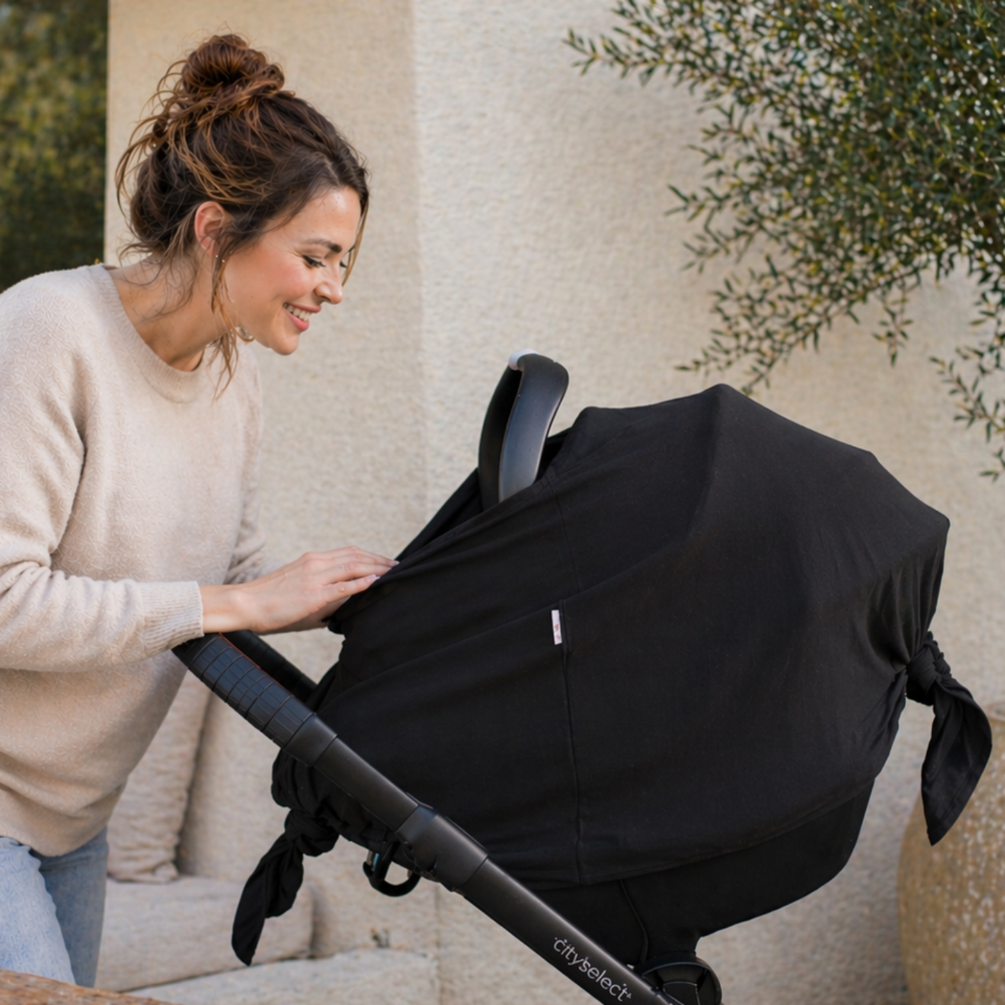 Woman setting up a black stroller with baby leaf cover outdoors