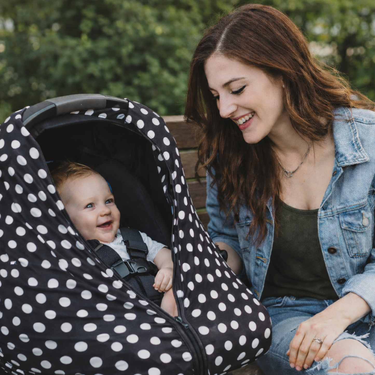 Woman sitting on a bench with a baby in a polka dot car seat