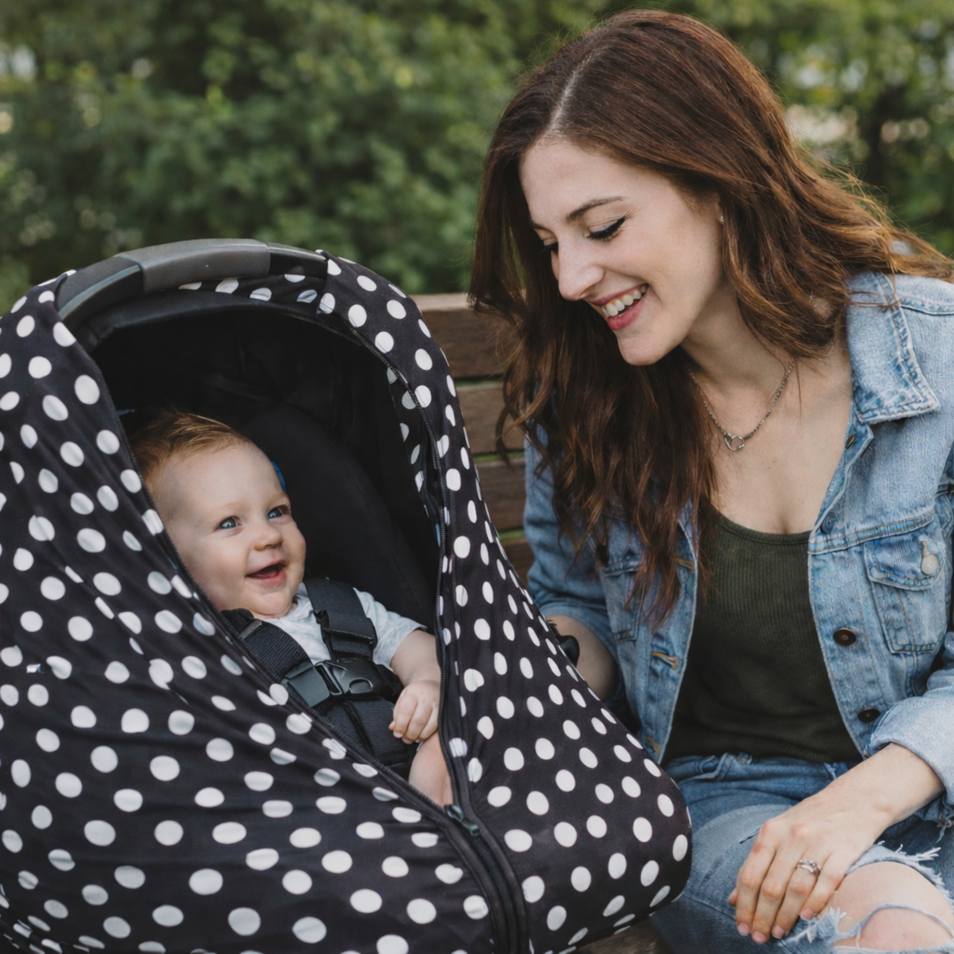 Woman sitting on a bench with a baby in a polka dot car seat