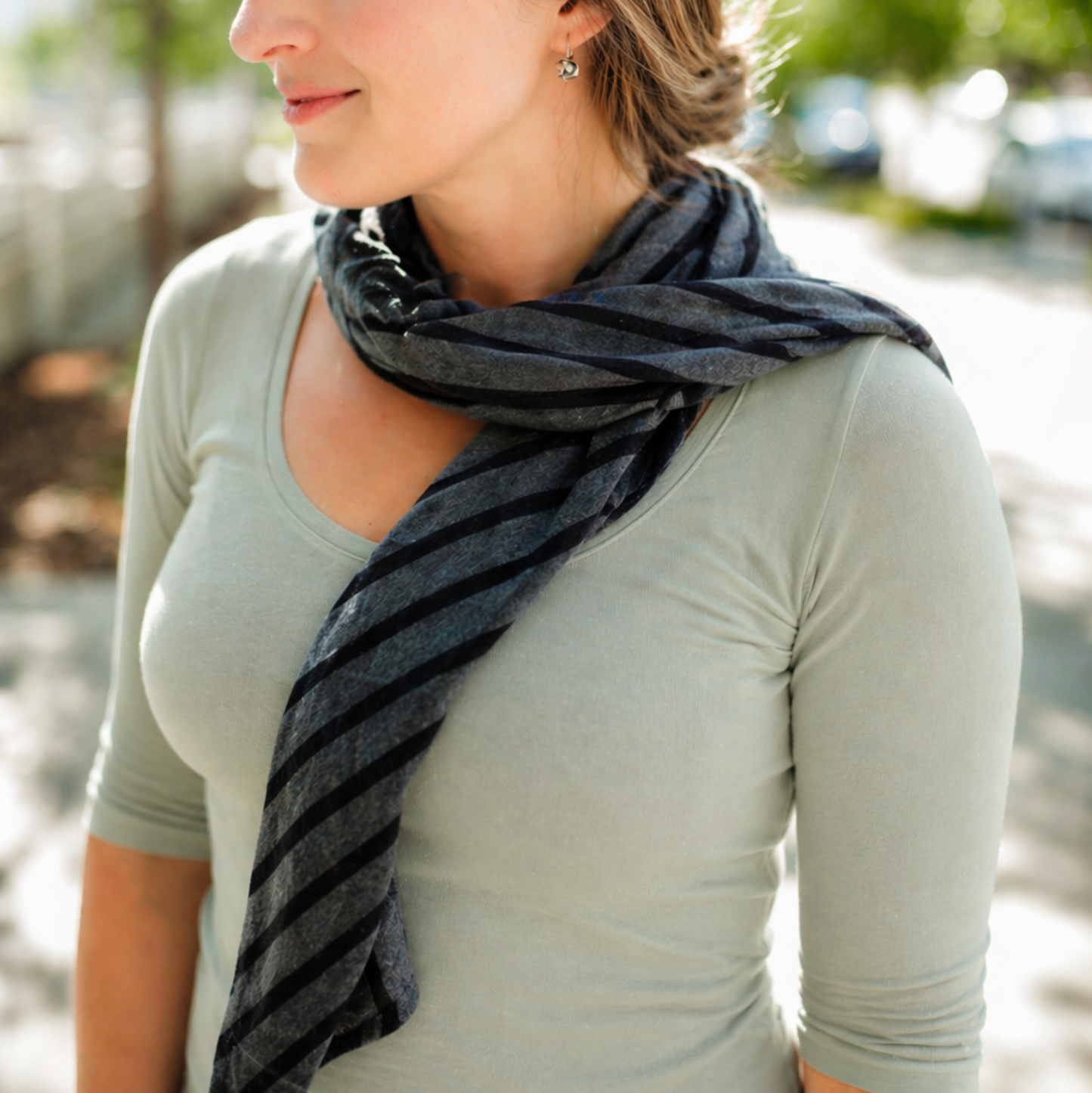 Woman wearing a gray scarf outdoors with blurred background
