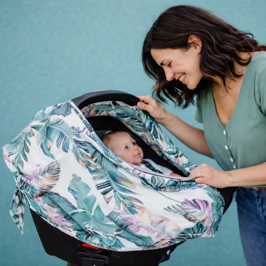 New mom opening a palm leaf-patterned baby leaf car seat cover for a baby