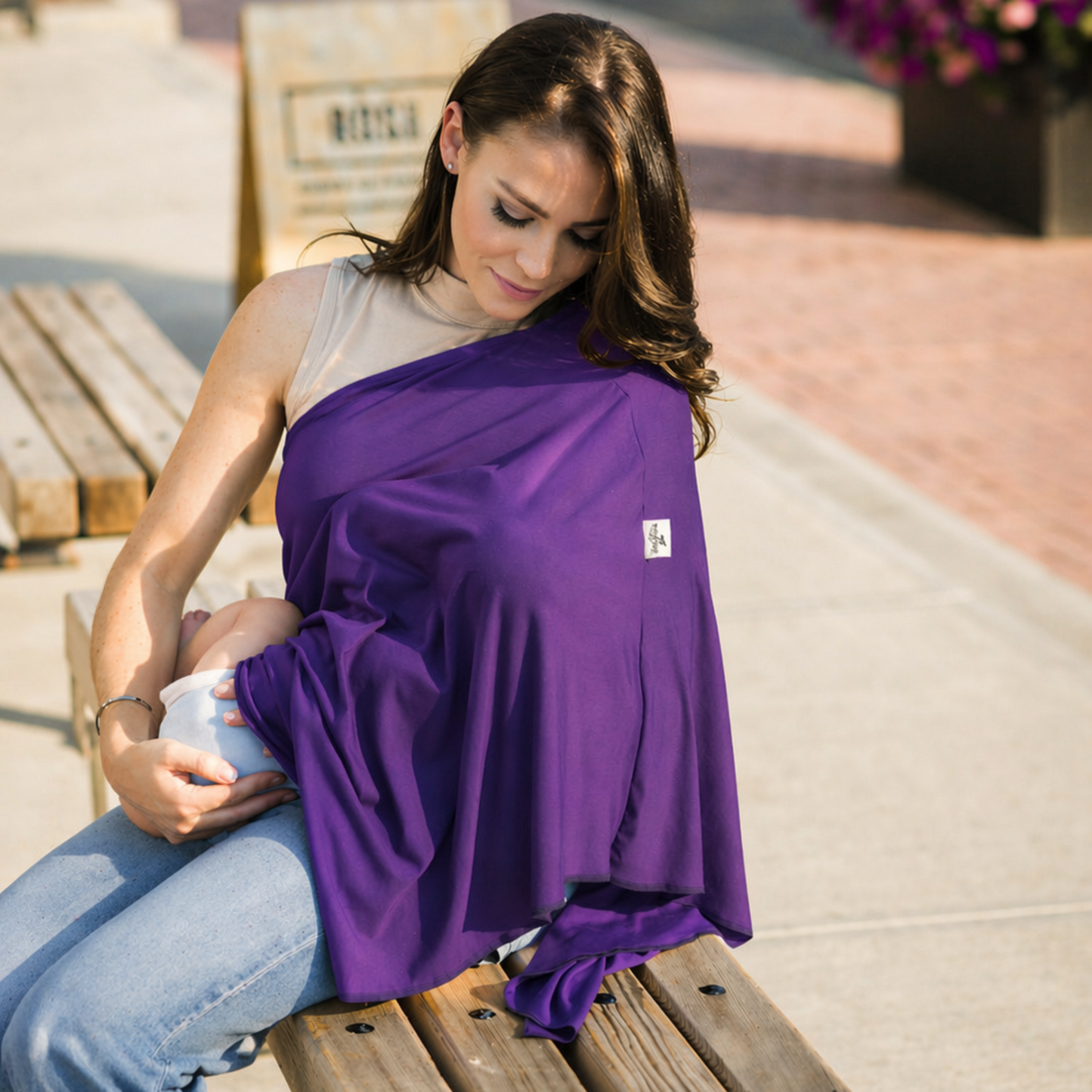 Woman sitting on a bench with a purple nursing wrap, outdoors.