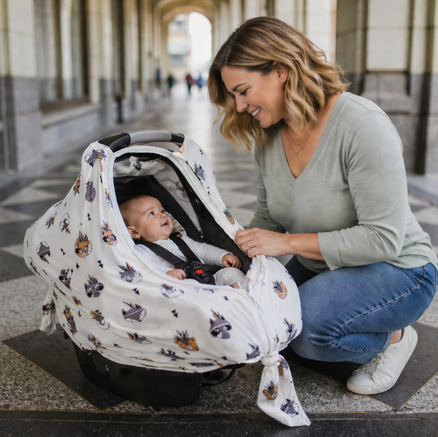 Woman adjusting a baby carrier with a baby inside on a city street.